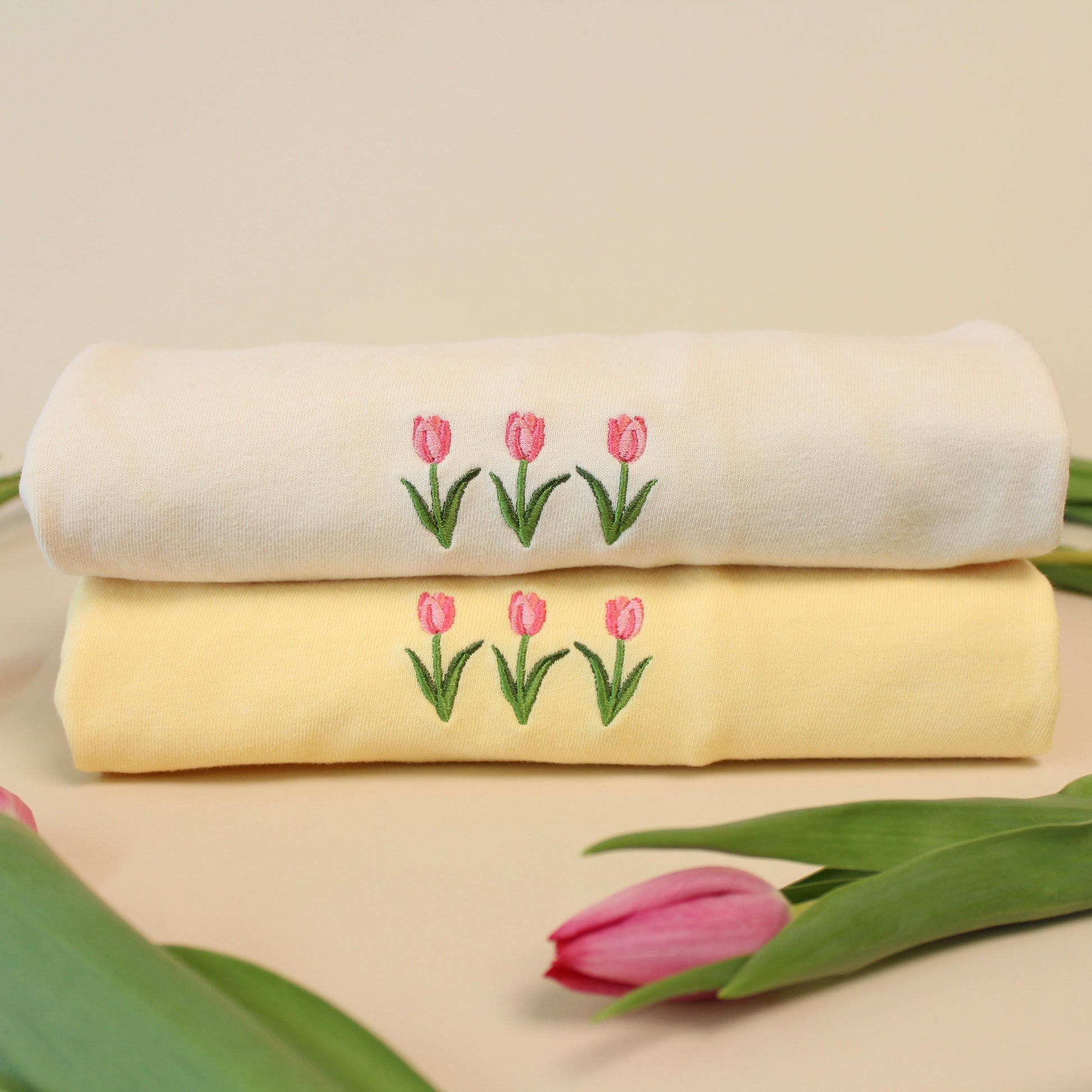 two folded t-shirts with three tulips embroidered on the front
